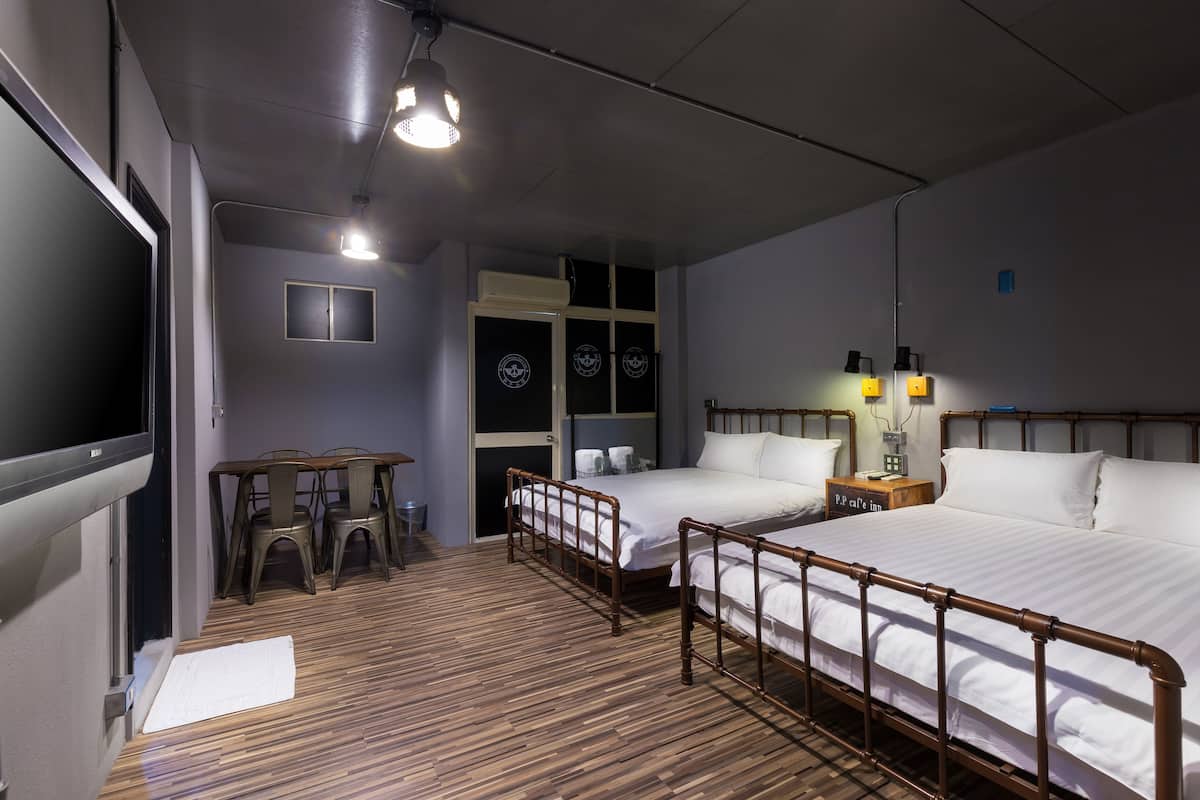 A hotel room with two beds, a TV, a desk, and a chair.