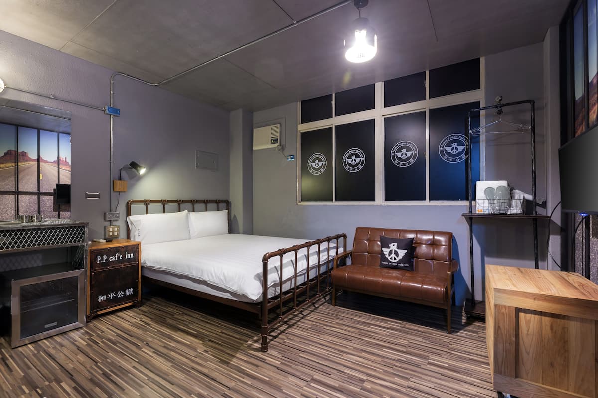 A bedroom with a wooden floor, a bed, a leather chair, a wooden cabinet, and a wall with circular windows.