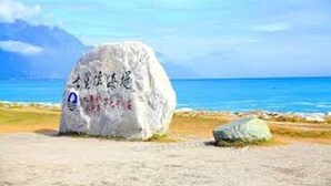 A large rock with inscriptions and a blue sign with a white symbol.