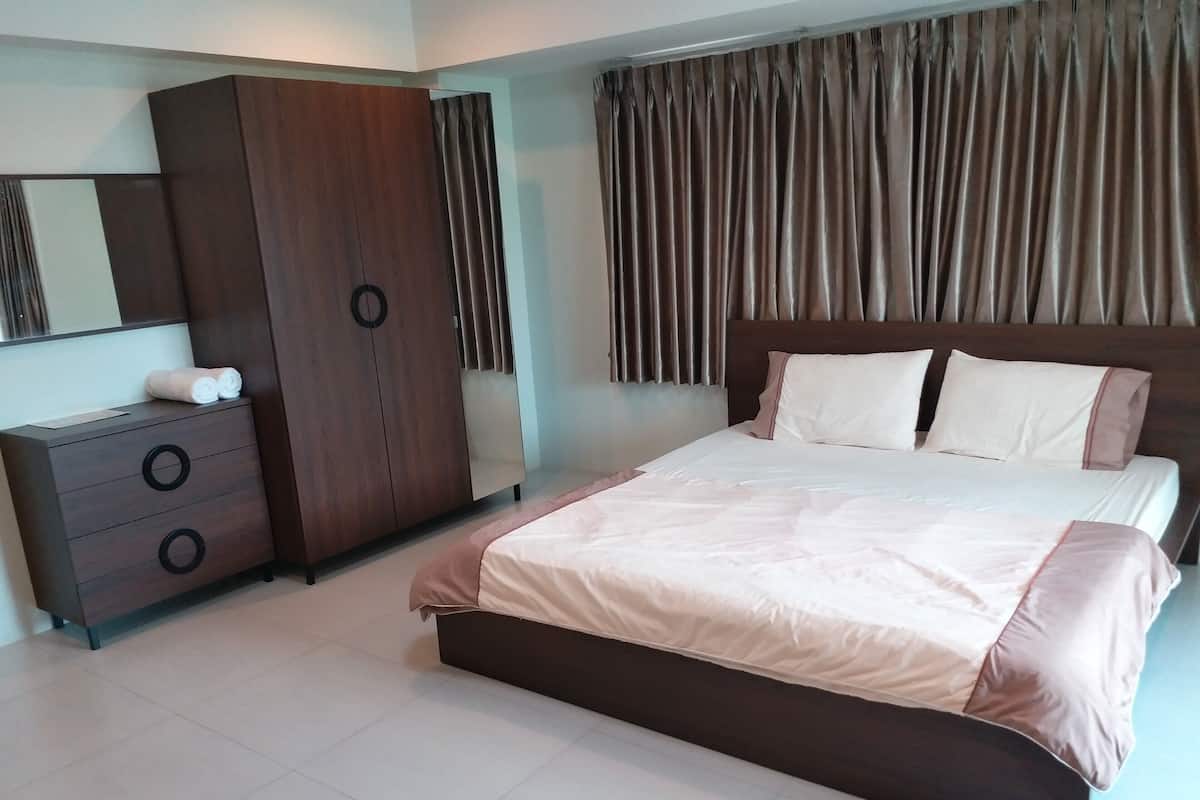 A bedroom with a bed, a wardrobe, and a mirror.