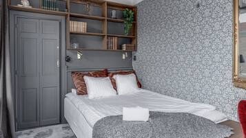 Ein Schlafzimmer mit einem Bett, einem Kleiderschrank, einem Regal mit Büchern und Dekoration sowie einer Wand mit Muster.