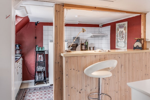 Una cocina con mostrador de madera, un taburete blanco y una pared roja.