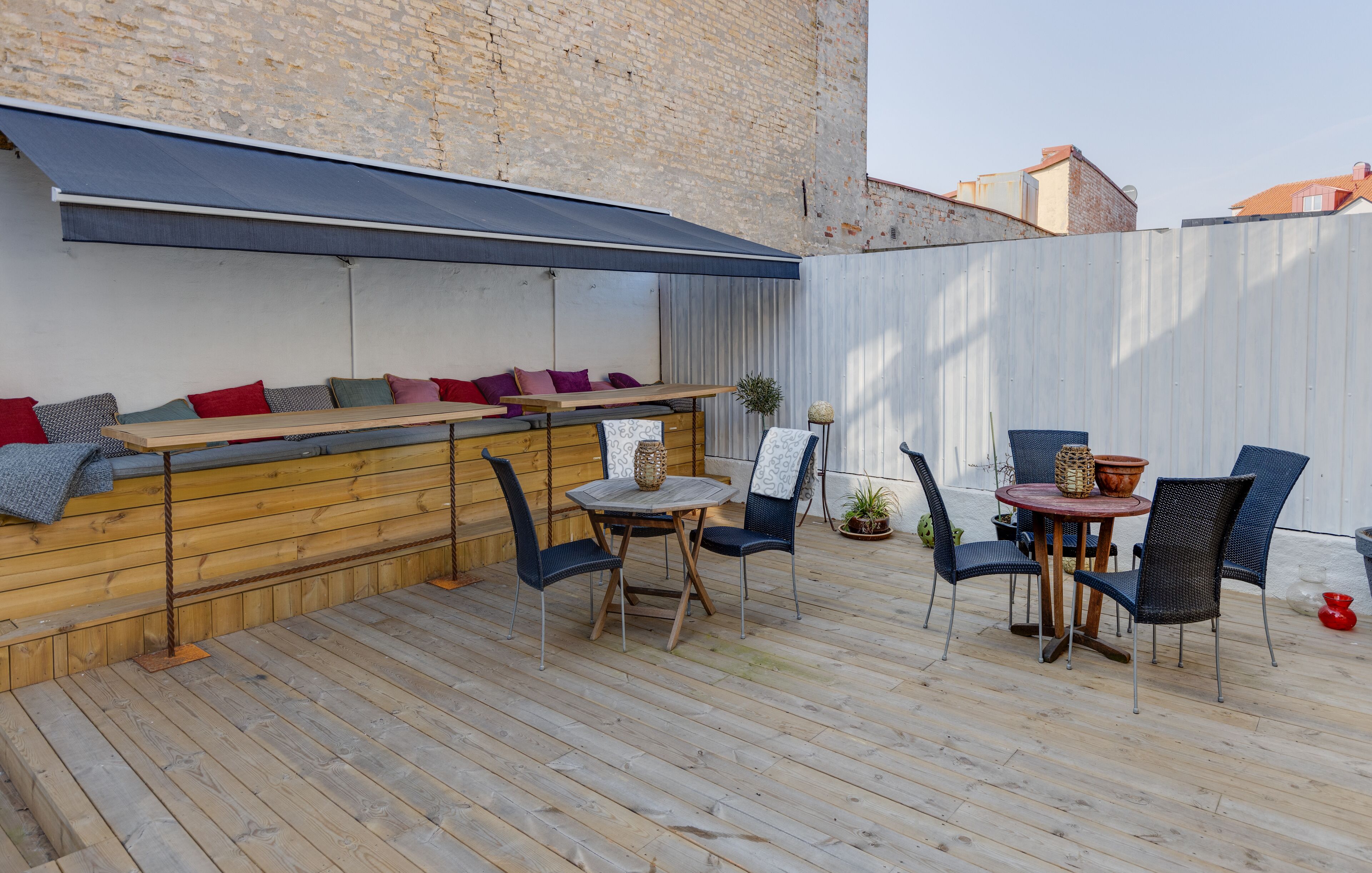 A wooden deck with a seating area, a table, and chairs.