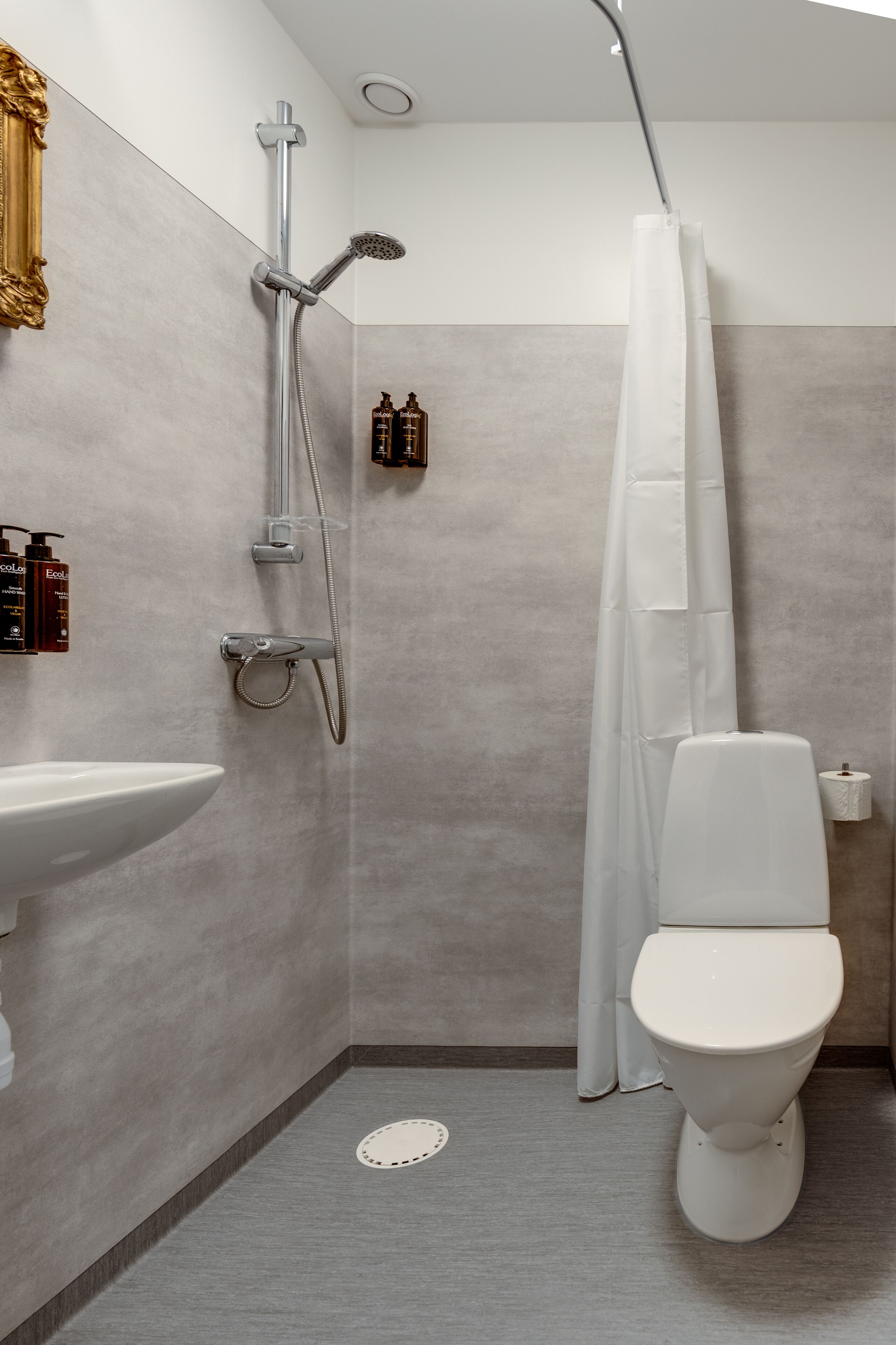 A modern bathroom with a shower, toilet, sink, and a towel rack.