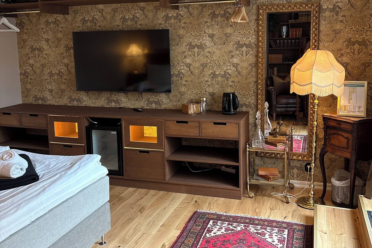 Un salon moderne doté d’un téléviseur à écran plat, d’un meuble de rangement en bois et d’un tapis à motifs.