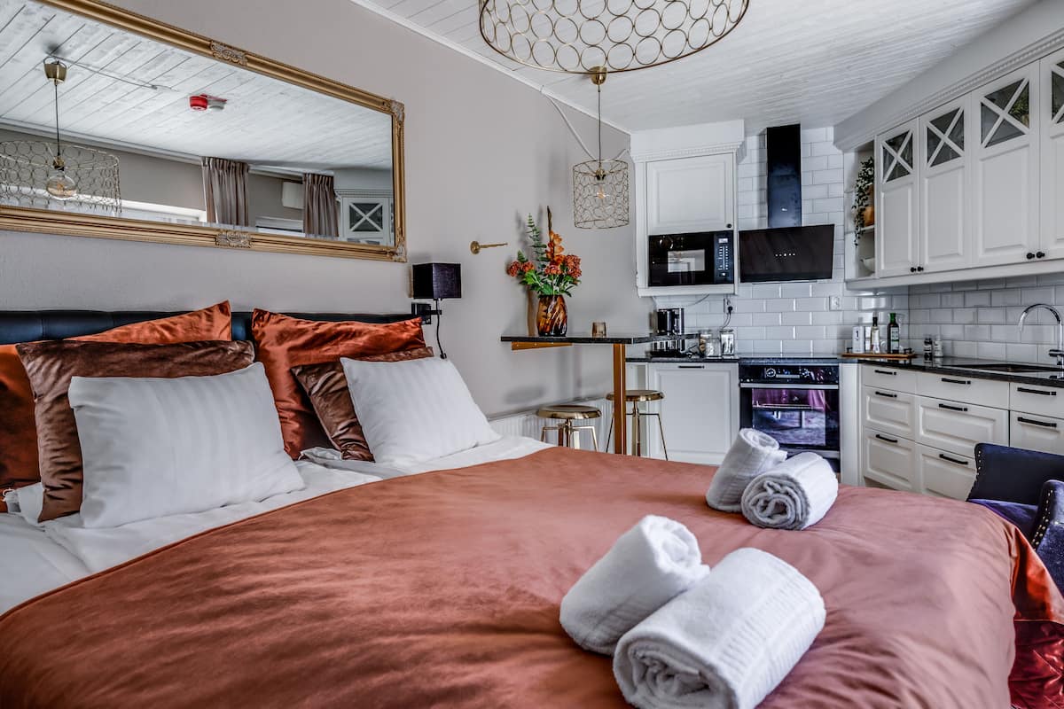 Une chambre d’hôtel avec un grand lit, un coin cuisine doté de meubles blancs, un four à micro-ondes et une télévision.