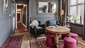 Ein Zimmer mit einem runden Holztisch, einem blauen Sessel und einem roten Teppich.