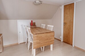 Un comedor con una mesa de madera, sillas blancas y una puerta de madera.