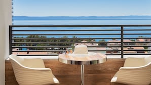 A balcony with two white chairs and a small table, overlooking a body of water and distant hills. - Hotel Ani (Makarska)