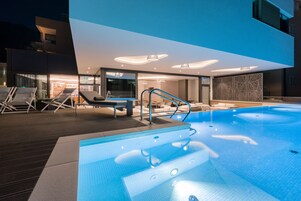 Una piscina al aire libre, sombrillas, sillones reclinables de piscina