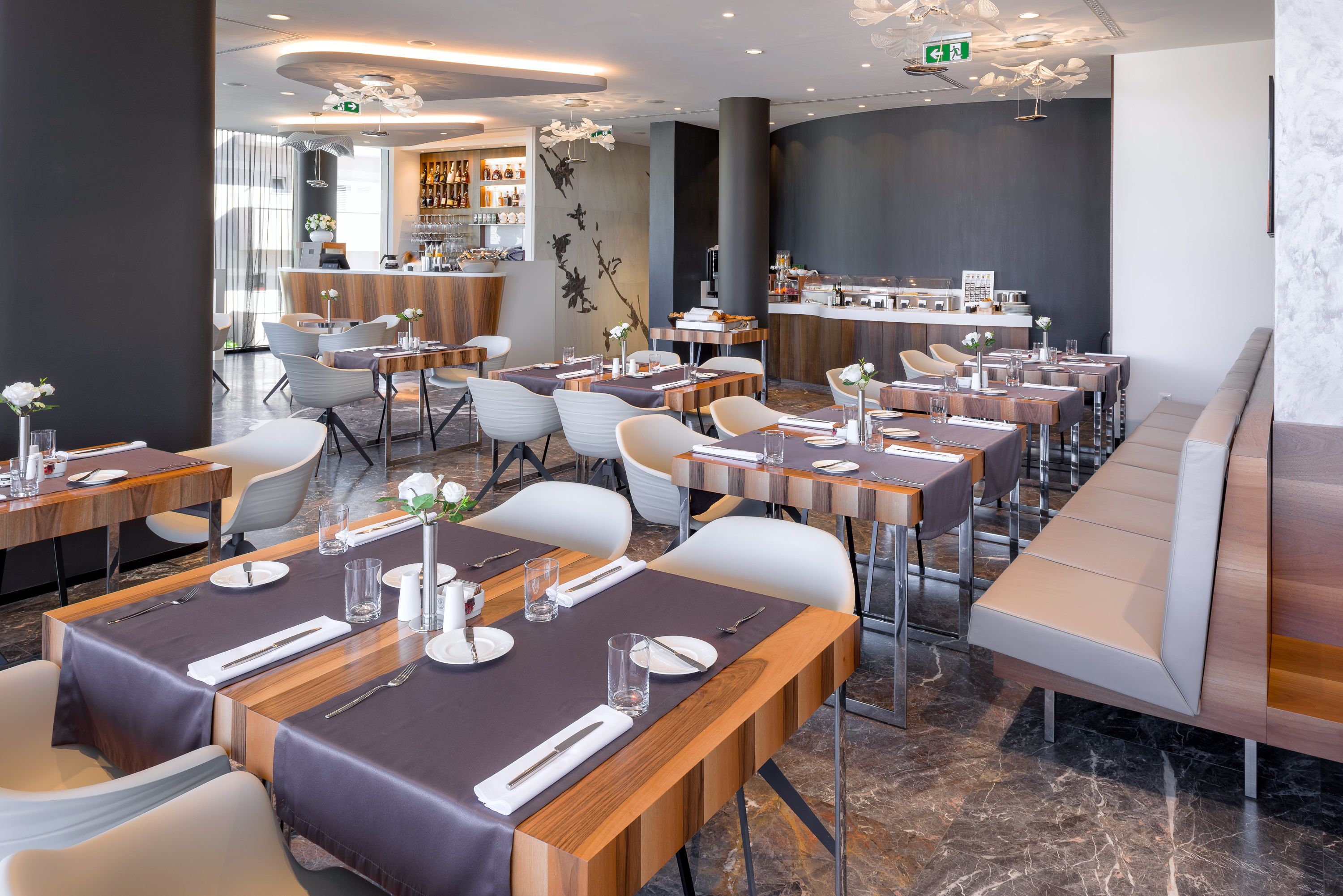 Un restaurant moderne doté de plusieurs tables, de chaises et d’un bar.