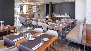Un restaurant moderne doté de plusieurs tables, de chaises et d’un bar.