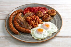 Un piatto con salsicce, uova, fagioli, funghi e pomodori.