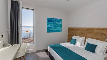 Una habitación de hotel con cama, escritorio y vista al mar.