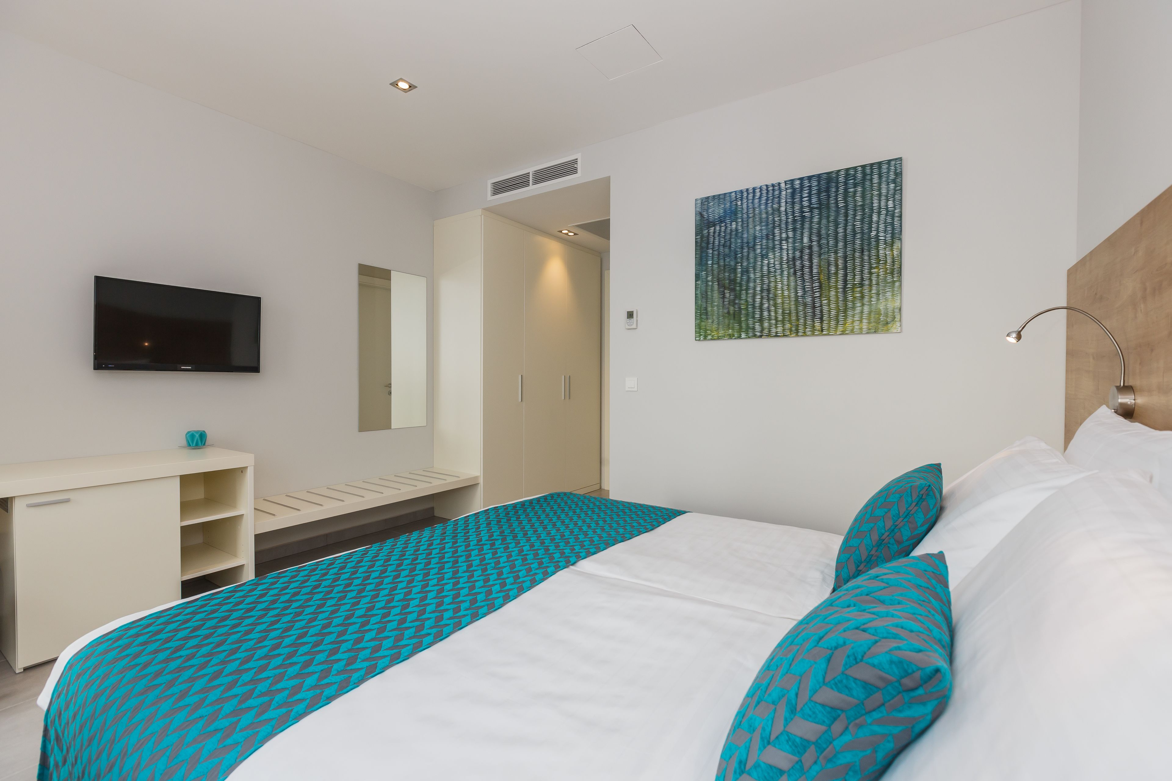 Habitación de hotel con cama, televisor, escritorio y armario.