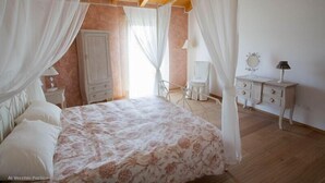 Een slaapkamer met hemelbed, een kledingkast, een kaptafel met spiegel en een nachtkastje.