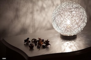 Una lámpara esférica de estructura metálica sobre una mesa con flores secas.