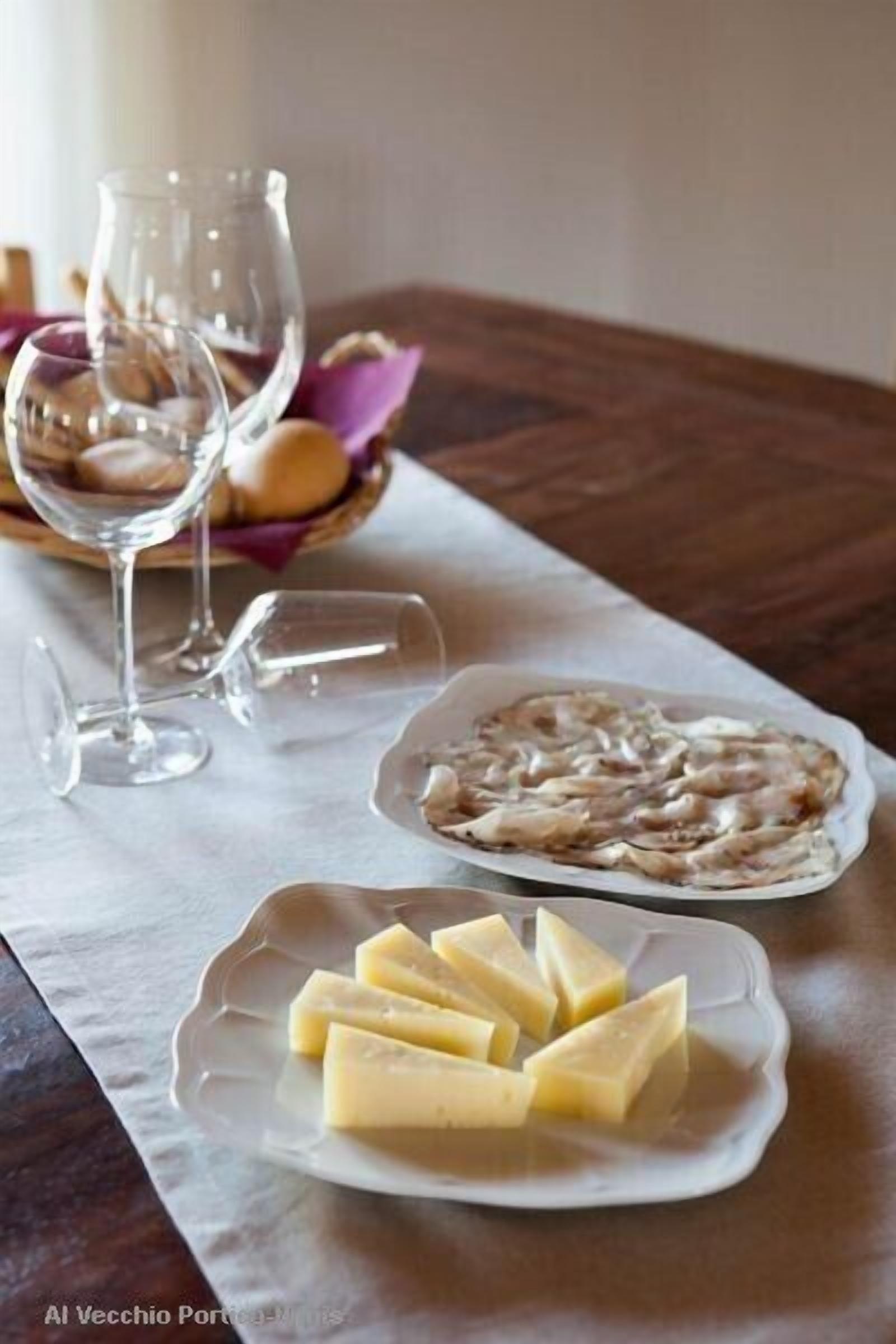 Une table avec une assiette de fromage, une assiette d’huîtres et deux verres à vin vides.