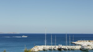 A marina with several sailboats docked, a yacht in the water, and a rocky shoreline. - Viva Mare Studios (Astypalaia)