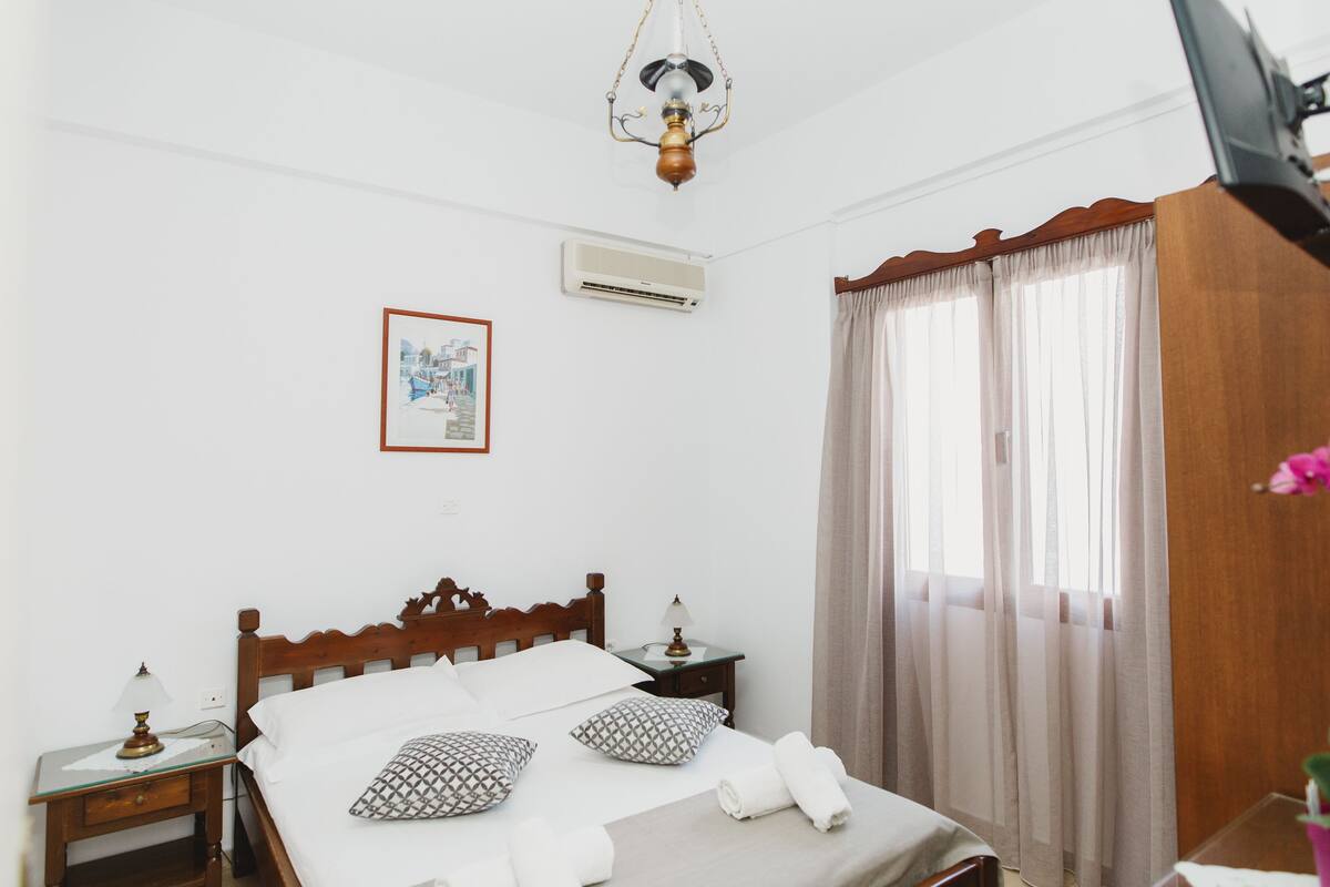 A neatly made bed with pillows, a bedside lamp, and a framed picture on the wall.