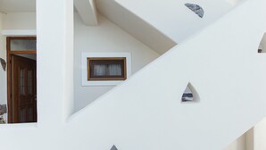 A white staircase with triangular cutouts and a small window with a wooden frame. - Viva Mare Studios (Astypalaia)