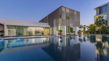 Un hôtel moderne doté d’une grande piscine, d’une façade en verre et d’une architecture contemporaine.