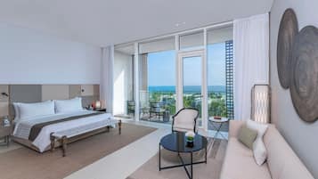 Ein modernes Hotelzimmer mit einem großen Bett, einer Couch, einem Couchtisch und einem Balkon mit Blick auf die Stadt.
