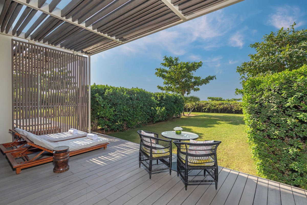 A deck with a sun lounger, two chairs, and a small table.