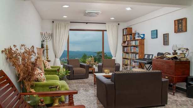 Una sala de estar con vistas, una estantería, un escritorio con computadora y un sofá verde.