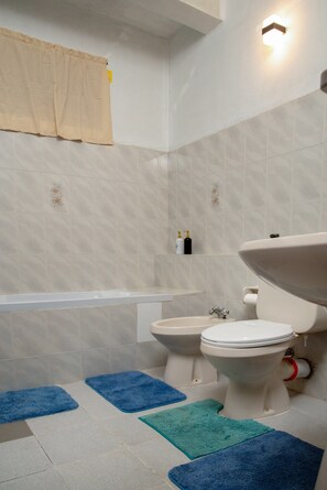 Une salle de bain comprenant des toilettes, un bidet, une baignoire et un lavabo.