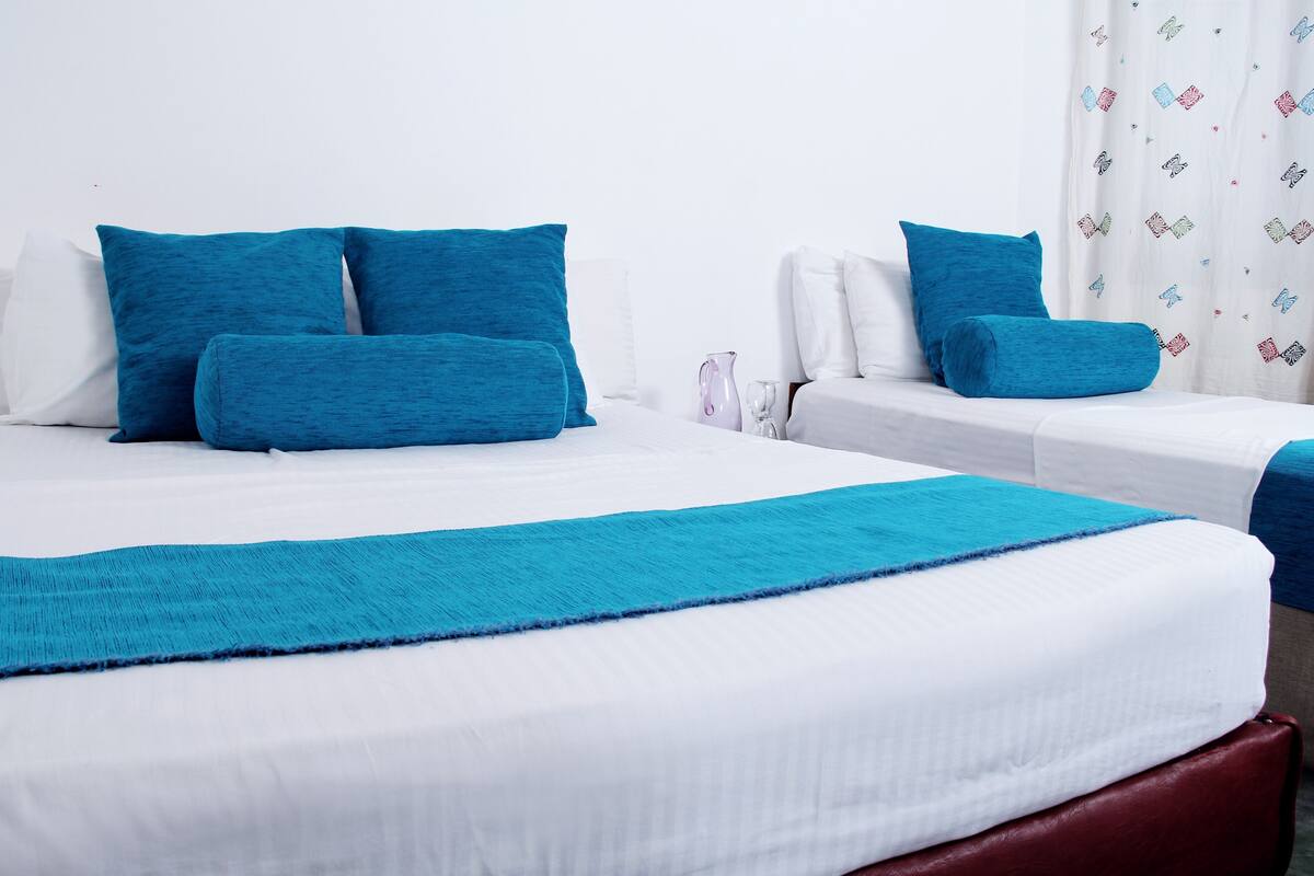 A hotel room with a large bed, two bedside tables, and a window with curtains.