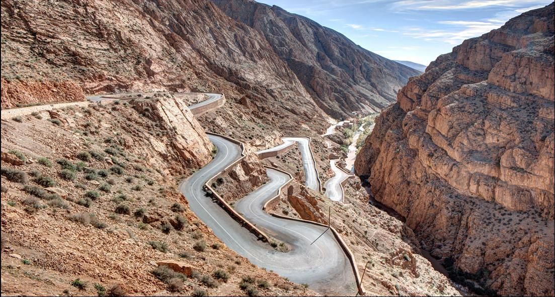 A winding mountain road with rocky terrain and sparse vegetation.