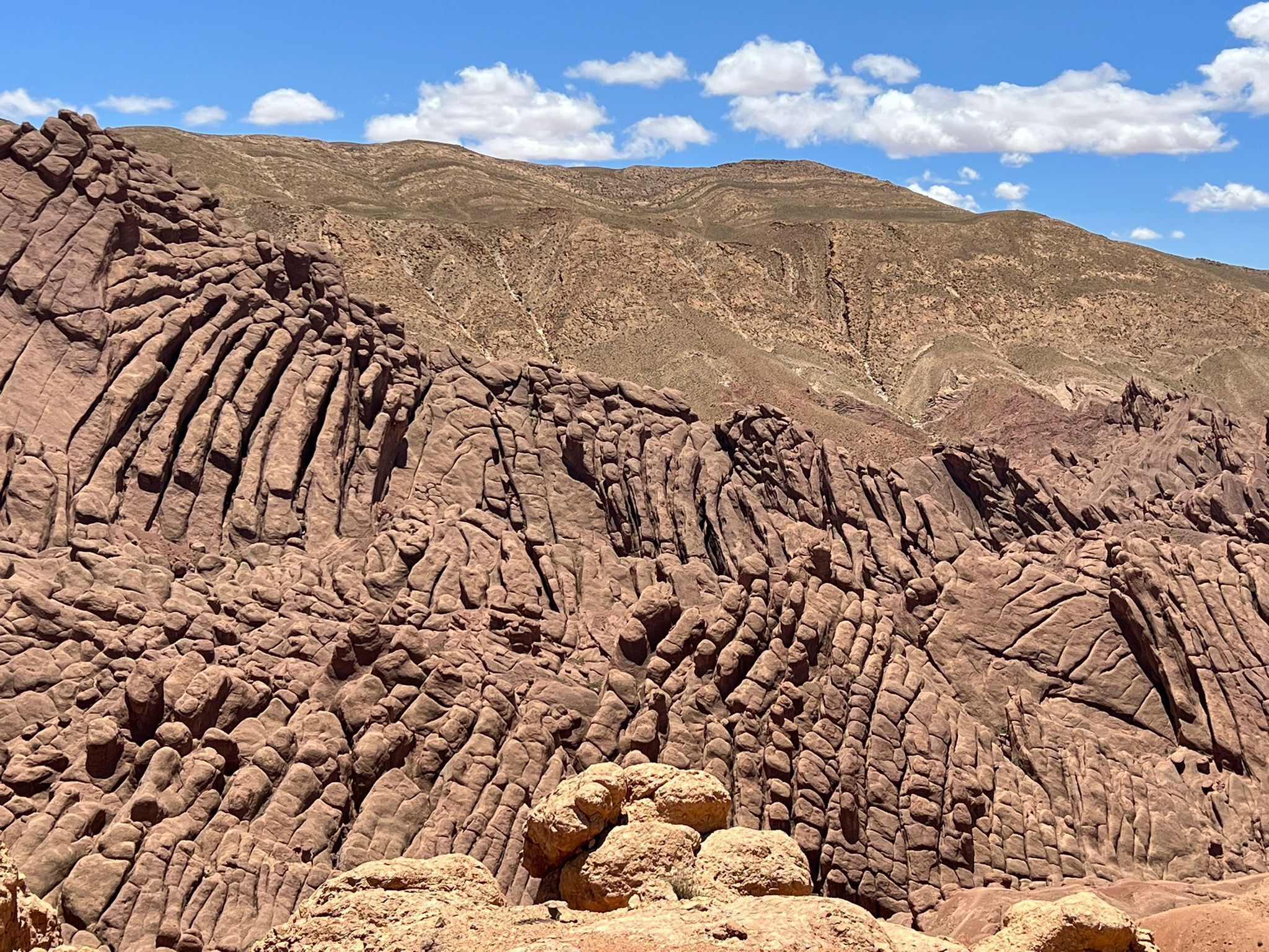 A rugged, rocky landscape with layered rock formations and a clear blue sky.