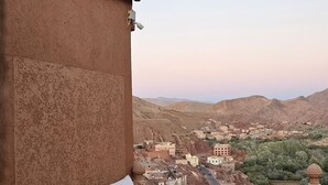 Un balcon avec un canapé, une petite table et une vue sur la ville et les montagnes.