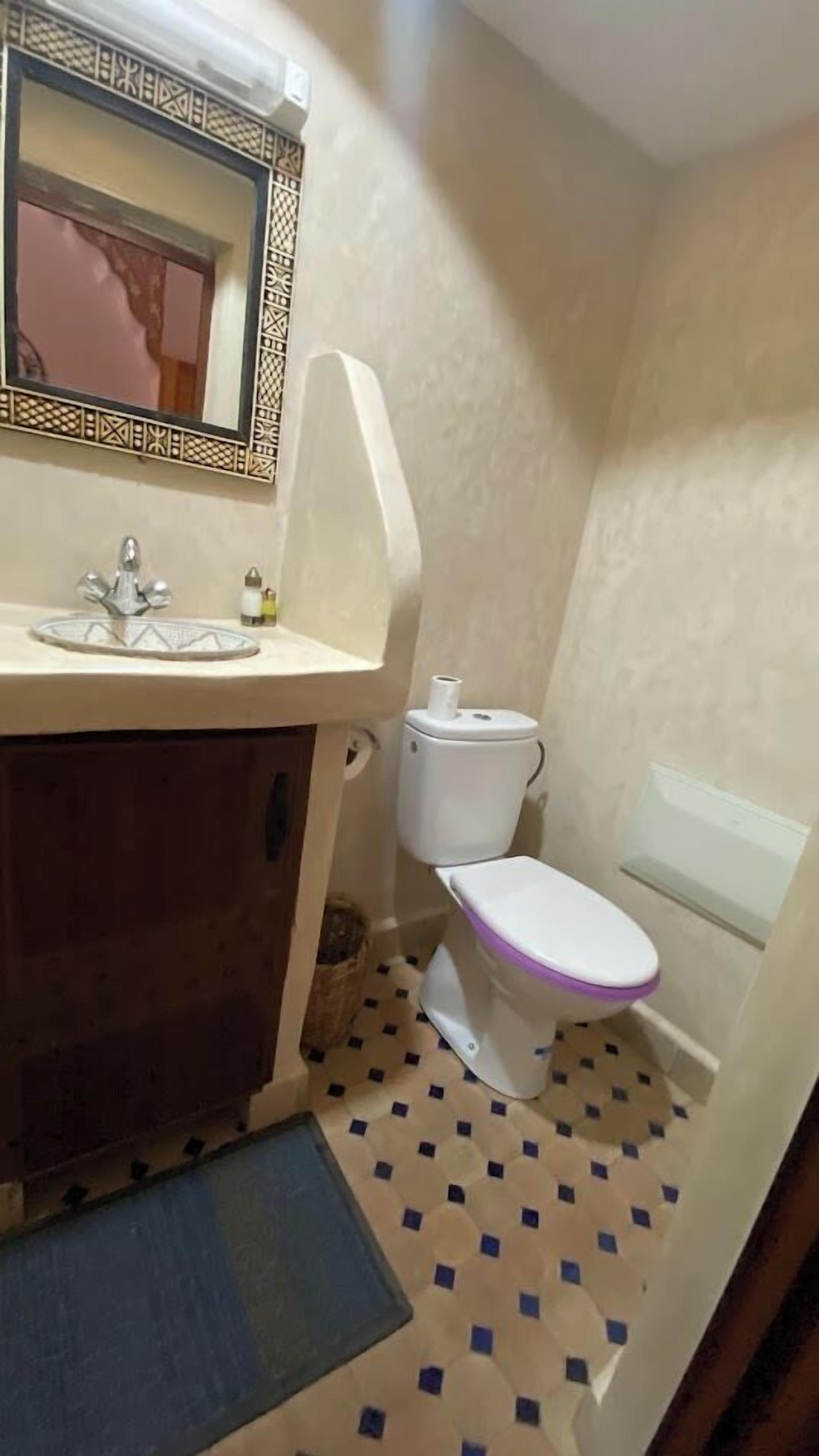 A small bathroom with a sink, toilet, and mirror.