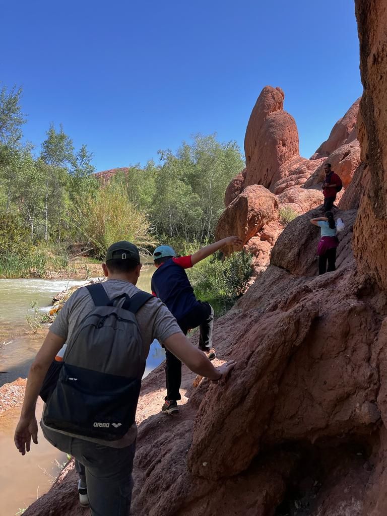 A group of people climbing a rocky outcrop near a river.