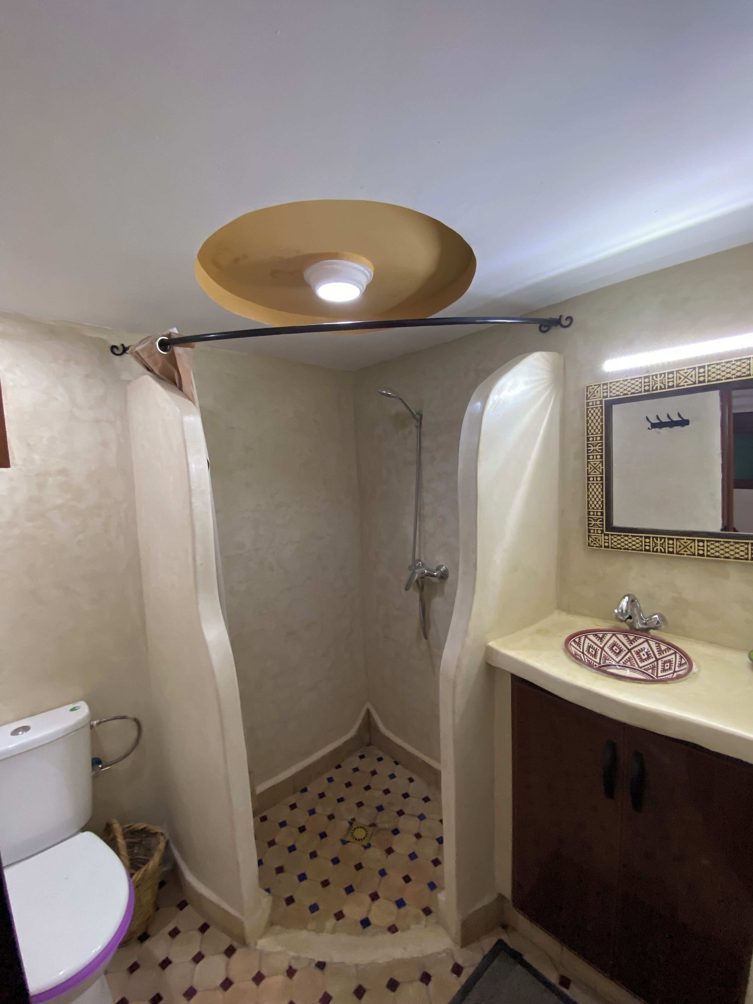 A bathroom with a shower, toilet, sink, and mirror.