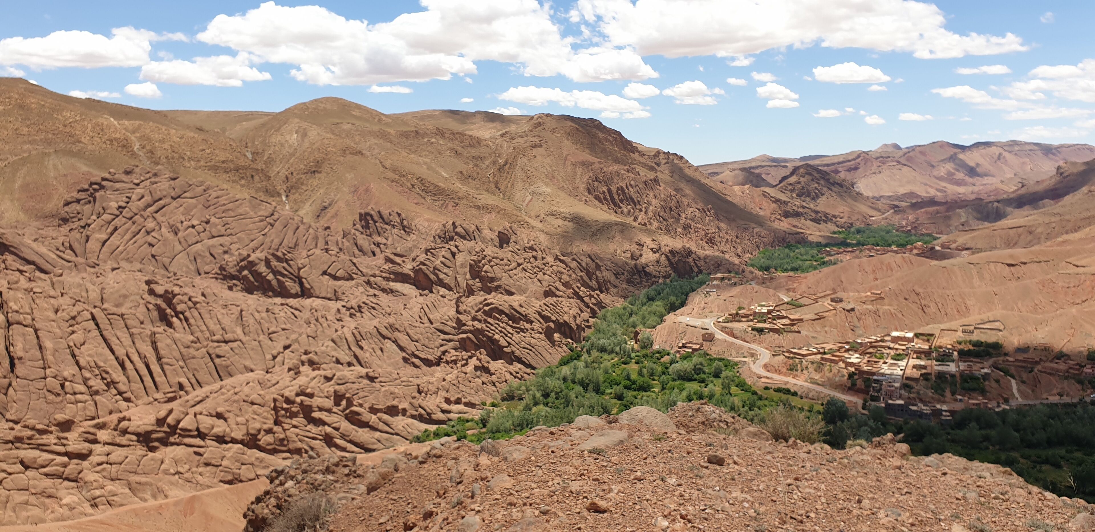 A rugged mountainous landscape with a winding road and a small settlement.