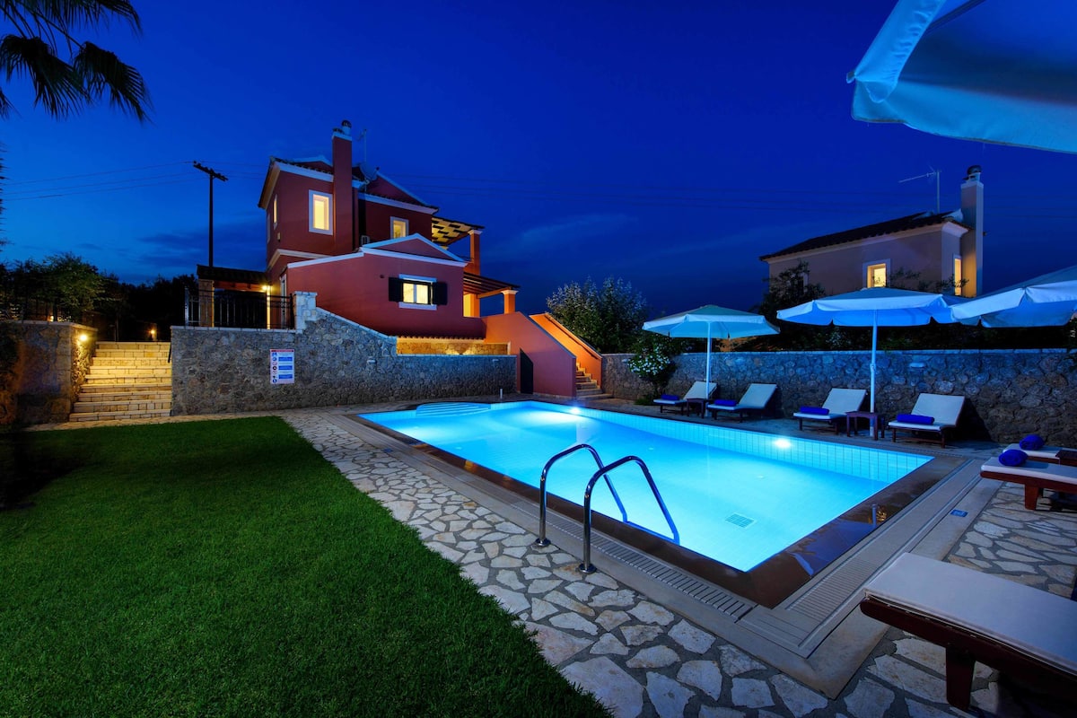 A swimming pool with a stone deck, lounge chairs, and umbrellas.