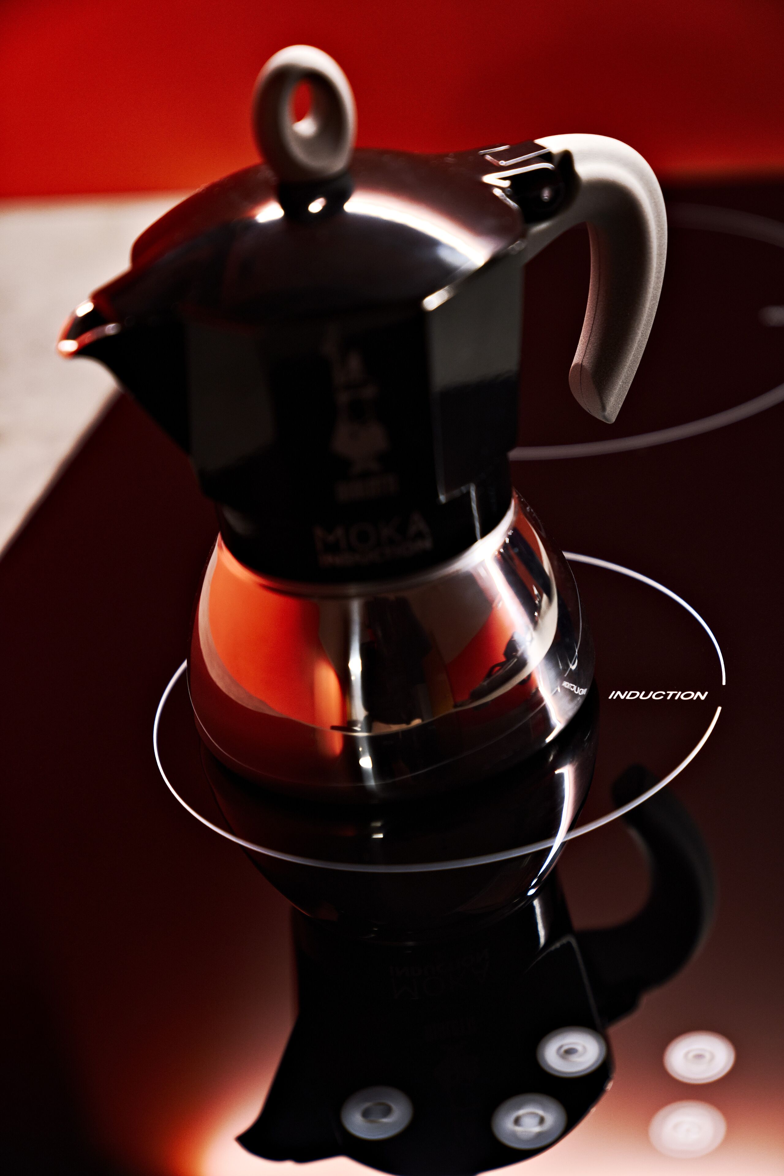 A black induction cooktop with a reflective surface and a control panel with buttons.