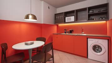 A compact kitchen with a dining area, a washing machine, and a pendant light.