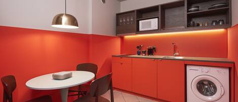 A compact kitchen with a dining area, a washing machine, and a pendant light.