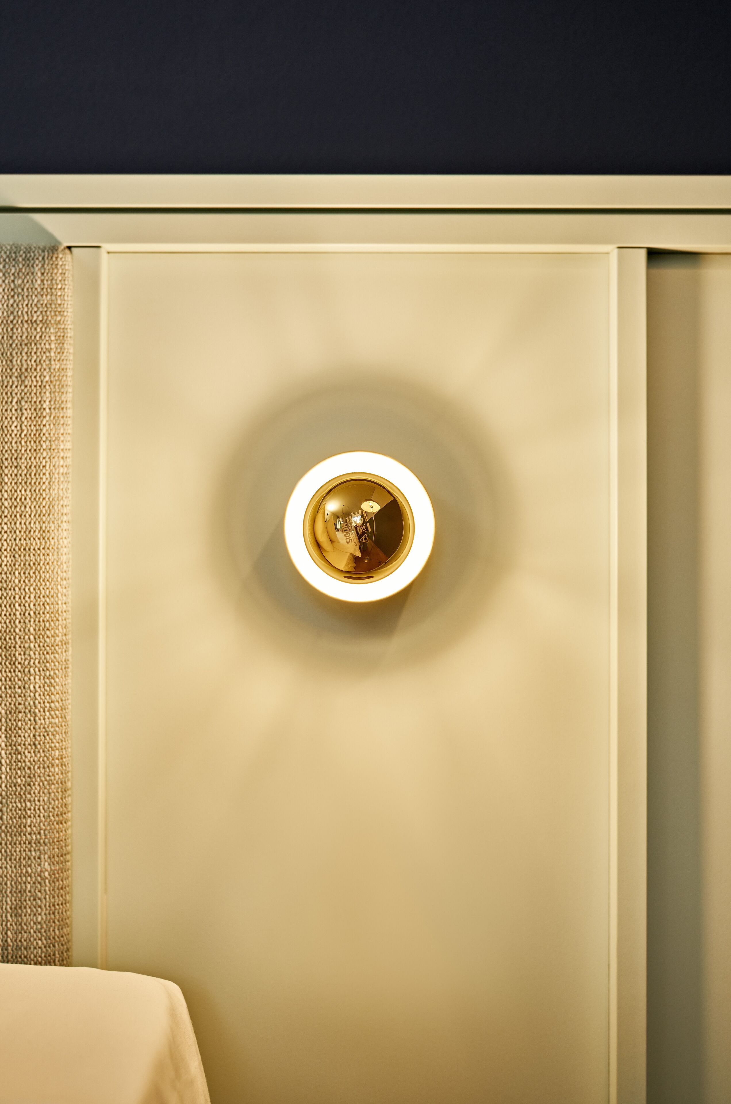 A wall-mounted light fixture with a circular design and a central knob.