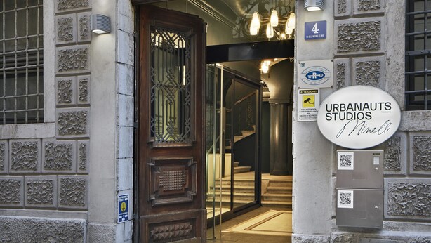 An entrance with a decorative archway, a sign for "URBANAUTS STUDIOS," and a QR code on the wall. - Urbanauts Studios Minelli (Trieste)