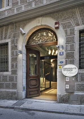 An entrance with a decorative archway, a sign for "URBANAUTS STUDIOS," and a QR code on the wall. - Urbanauts Studios Minelli (Trieste)