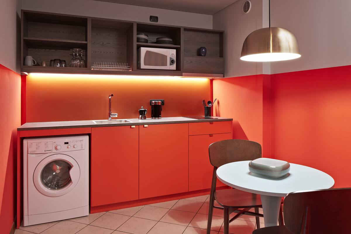 A compact kitchen with a washing machine, a microwave, and a coffee maker.