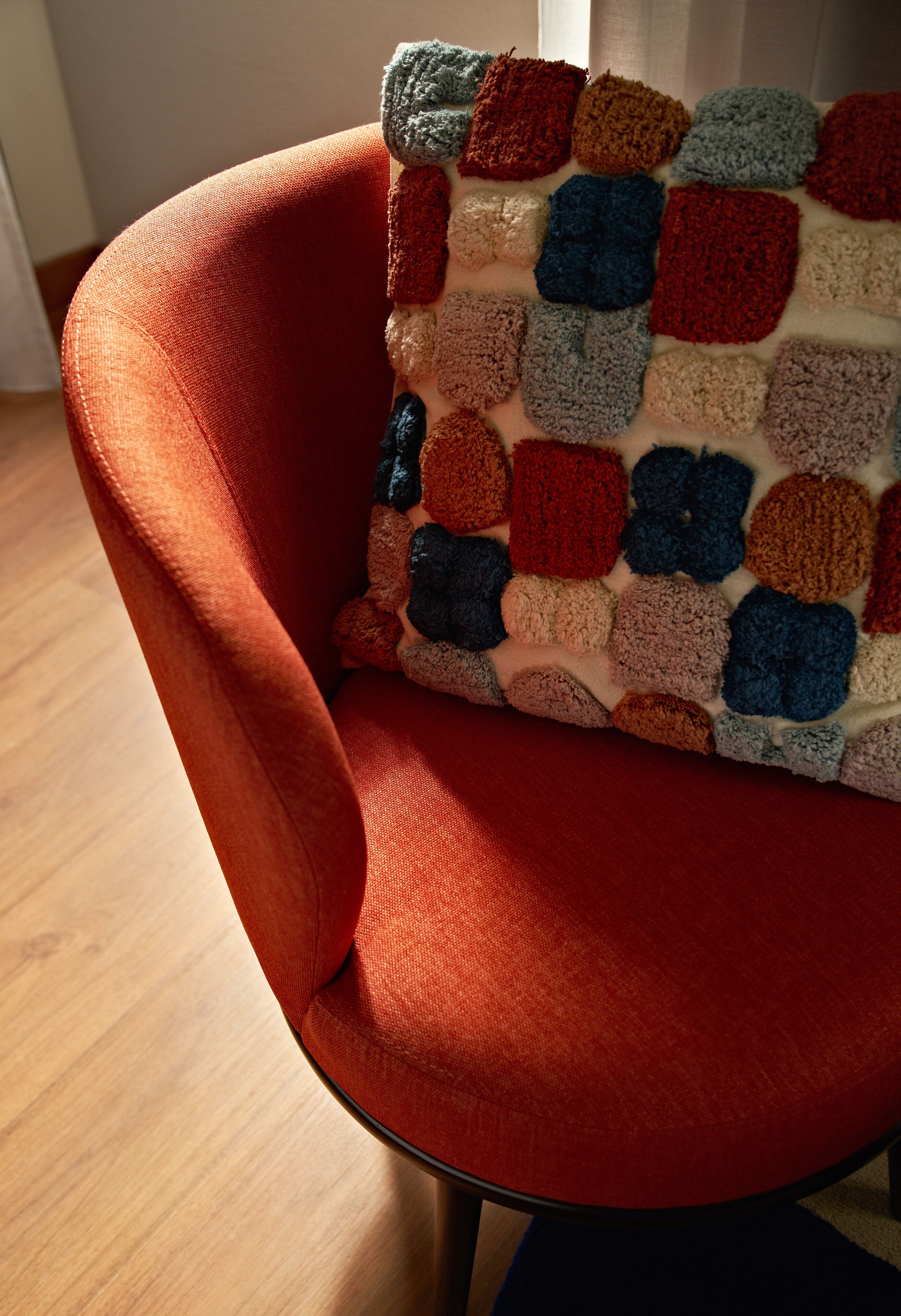 A red chair with a colorful, textured cushion.