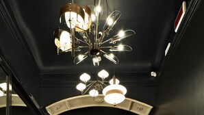A modern interior with a staircase, a chandelier, and a glass door with a sign. - Urbanauts Studios Minelli (Trieste)