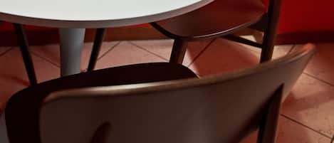 A round table with a white surface and a square object on it. A brown chair with a cushioned seat is positioned in front of the table.