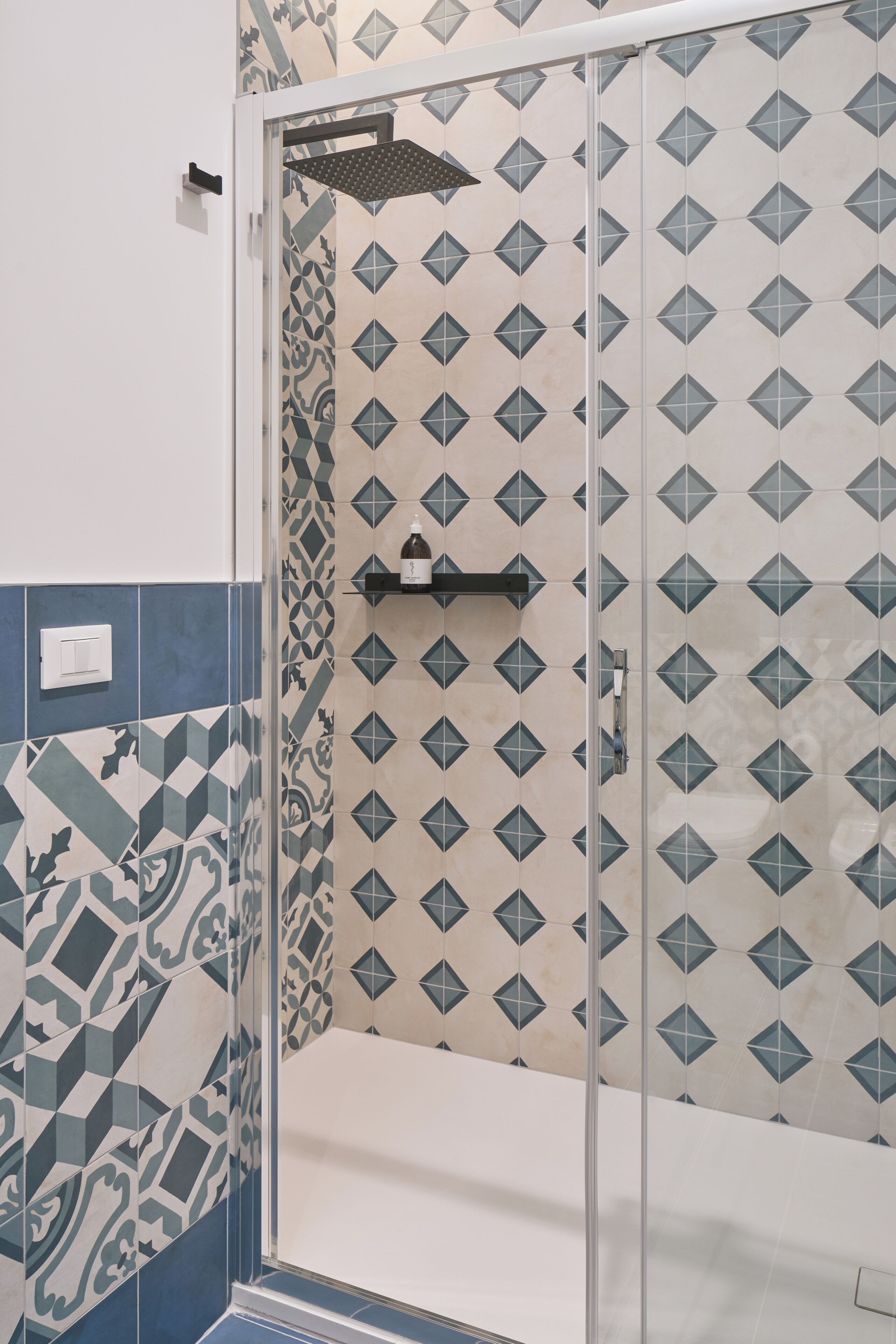 A bathroom with patterned tiles, a shower enclosure, and a white bathtub.